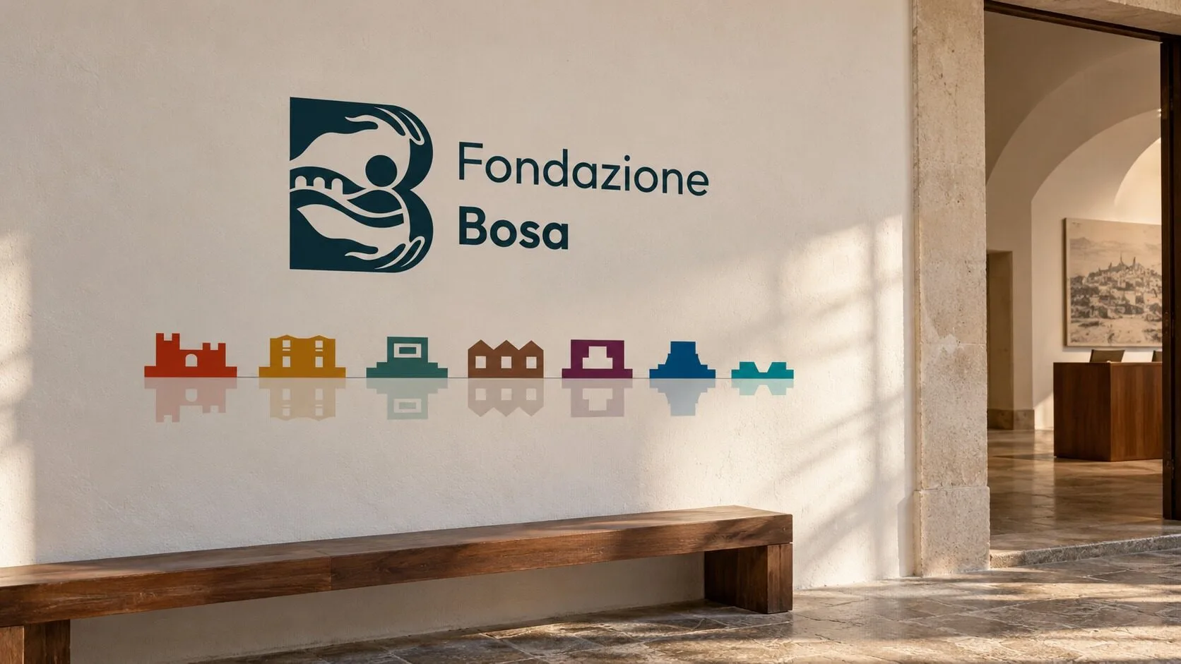 A light museum wall with the horizontal Fondazione Bosa mark in Blu Temo and, below it, the mirrored frieze of the seven sites in colour above a wooden bench